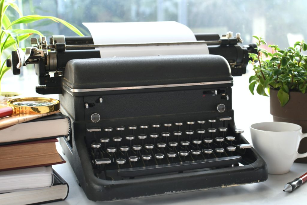 Vintage manual typewriter on desk with books - writer author concept
